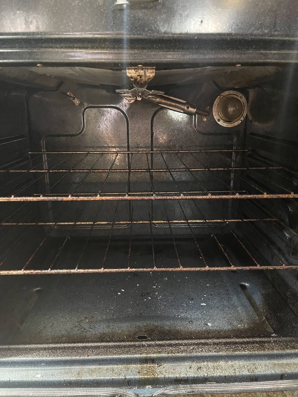 Oven interior before cleaning, with baked-on grease and residue